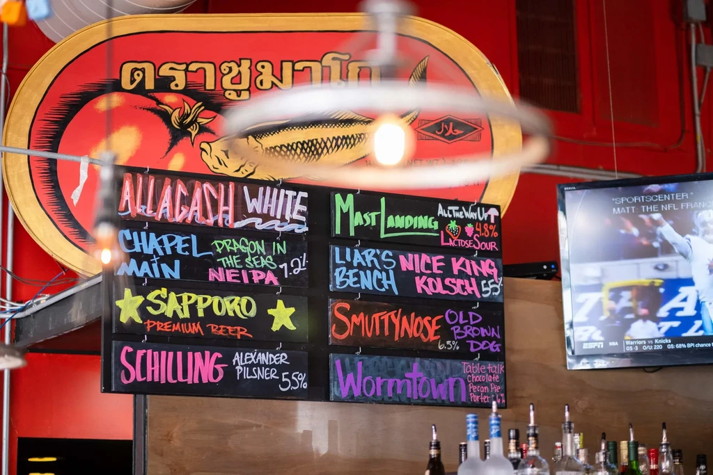 Vibrant bar interior with colorful chalk beer menus and a halal sign.