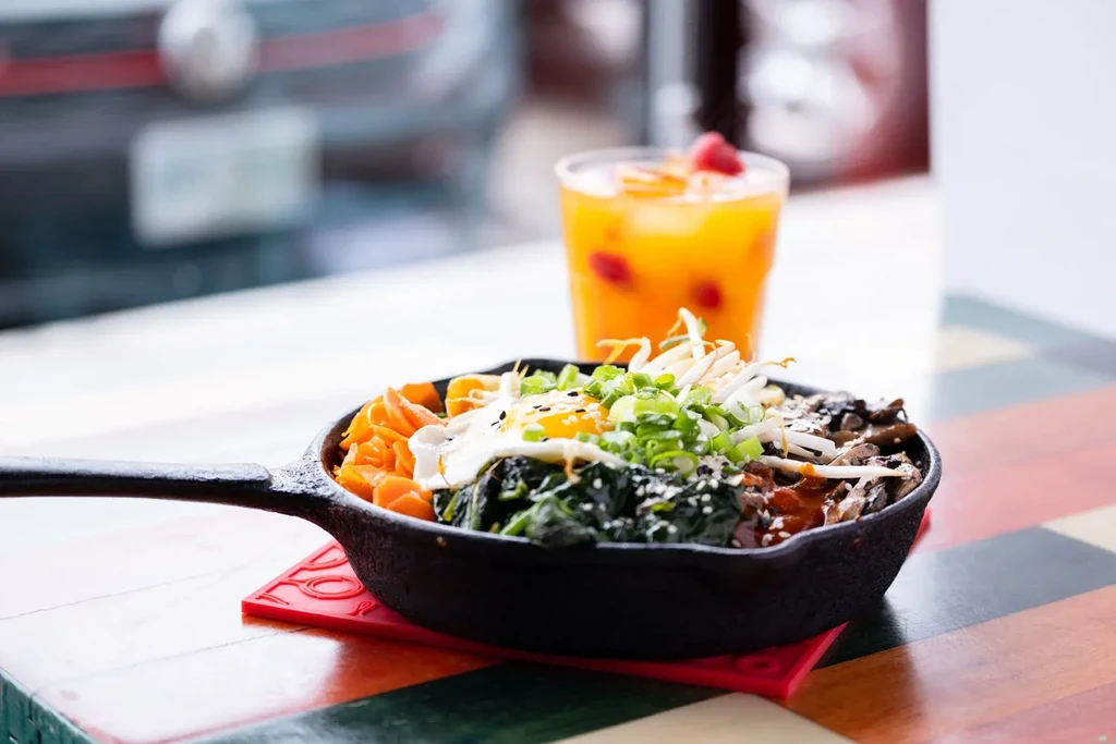 Colorful bibimbap in a black skillet with a sunny-side-up egg.