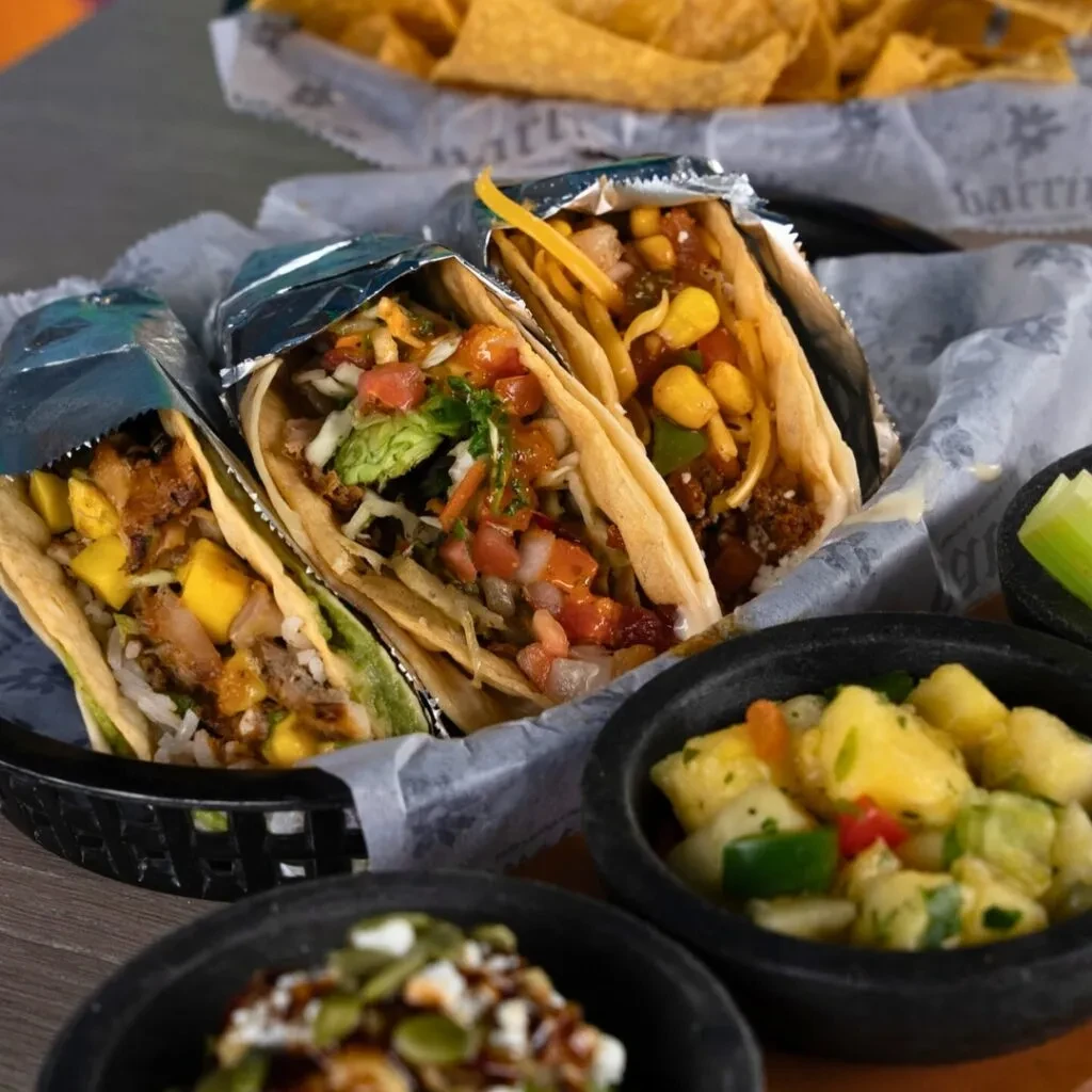 Close-up of three soft-shell tacos with varied fillings in a basket.