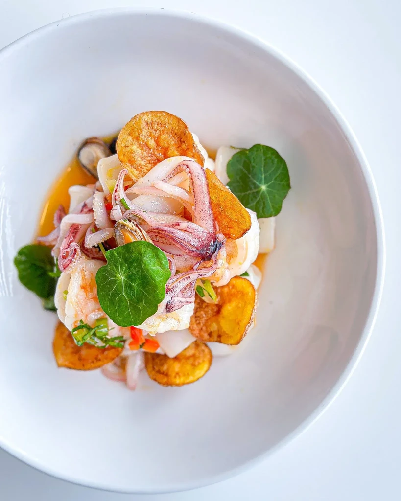 Cooked seafood dish with squid, shrimp, mussels, chips, and greens.
