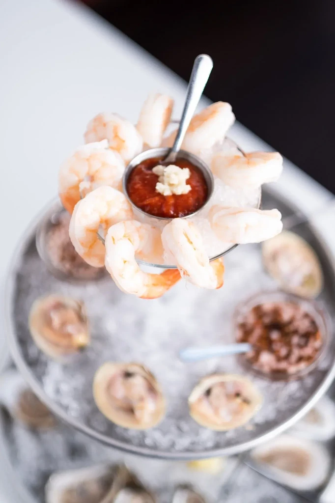 Multi-tiered seafood tower with shrimp, clams, oysters and sauces.