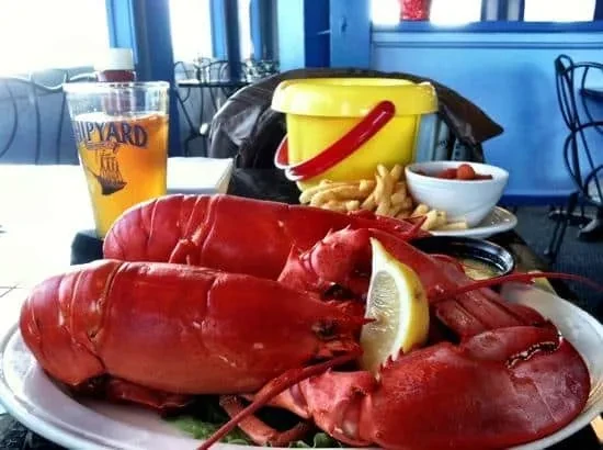 Two cooked lobsters, french fries, and Shipyard beer in a casual restaurant.