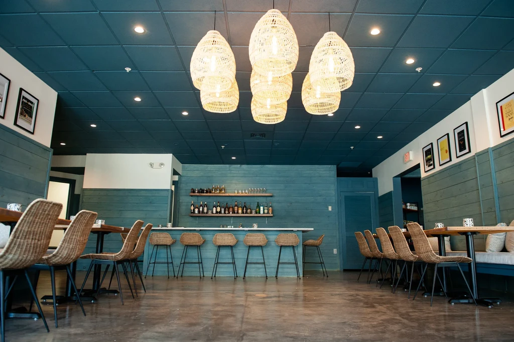 Teal-paneled restaurant interior with wicker furniture and a bar.