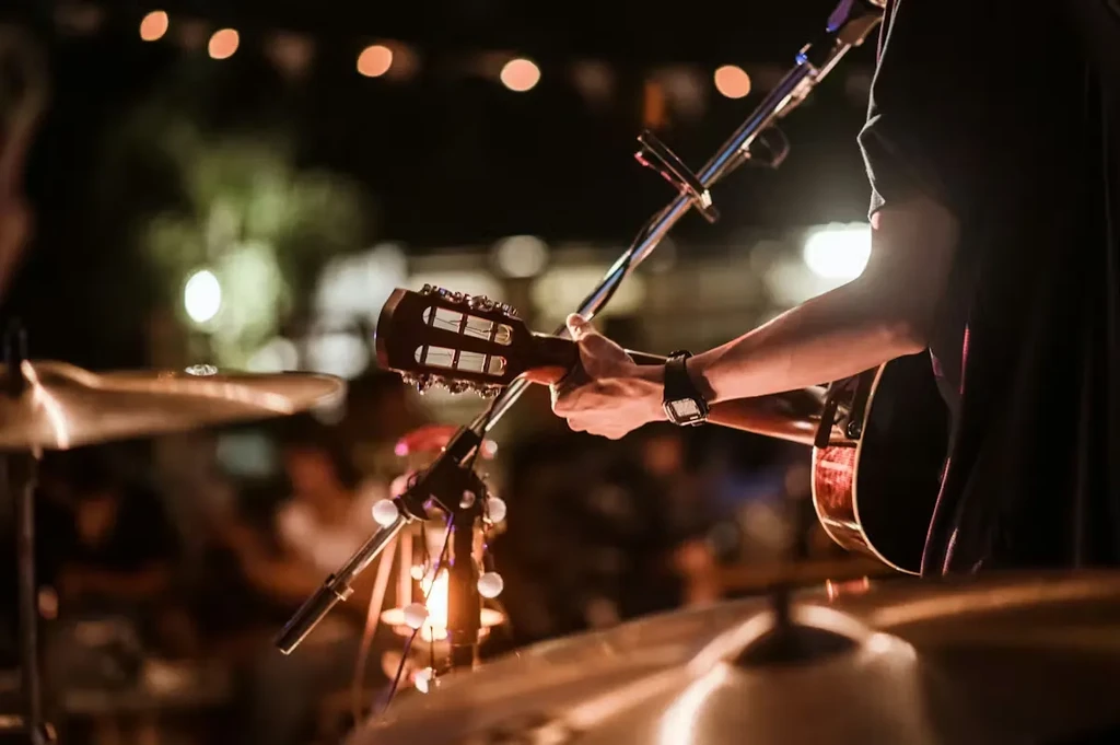 Close-up of musician's hands playing acoustic guitar, warm blurred background.