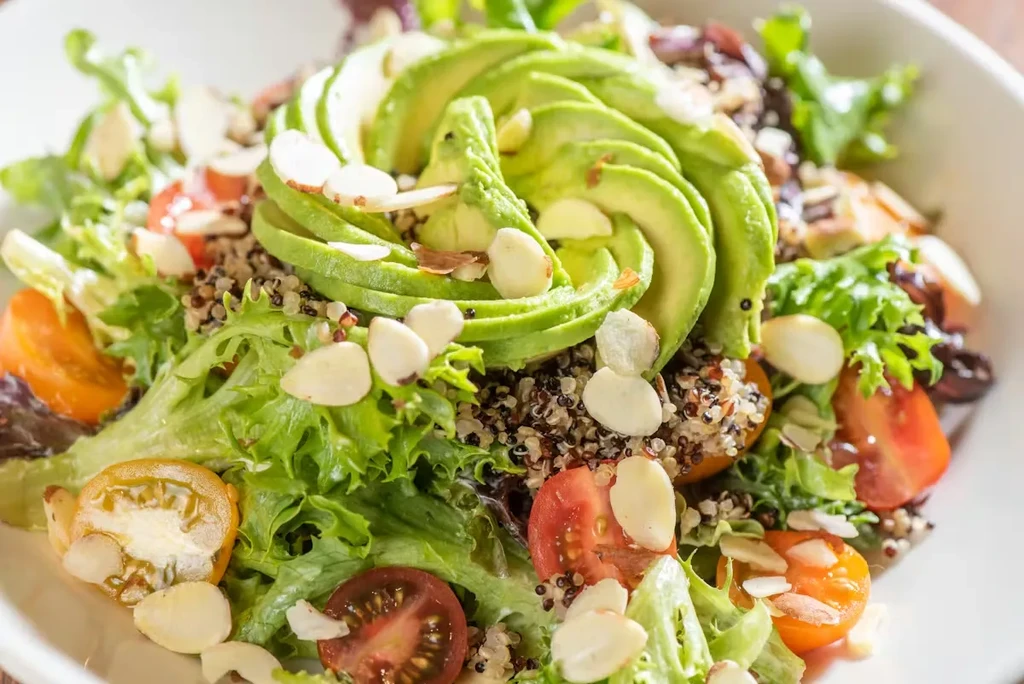 Salad with fanned avocado, mixed greens, tomatoes, quinoa, and almonds.