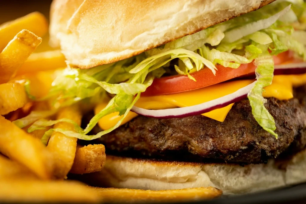 Well-lit cheeseburger with melted cheese, fresh toppings, and golden French fries.