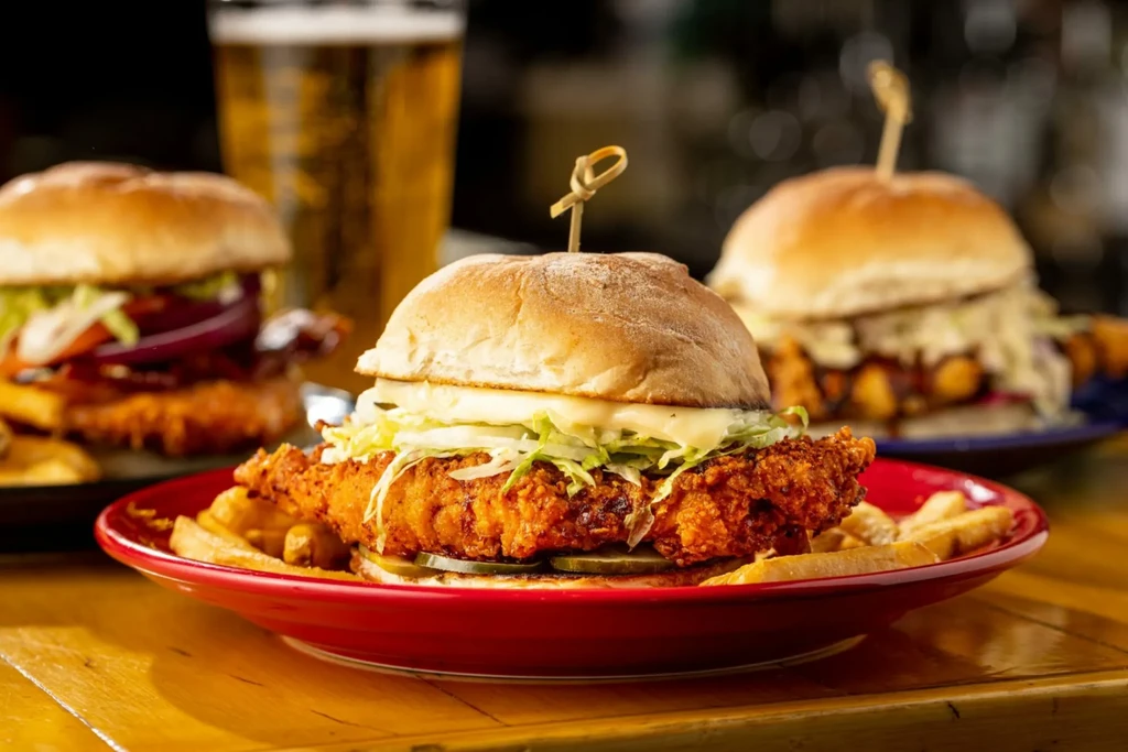 Crispy fried chicken sandwich with fries on a red plate.