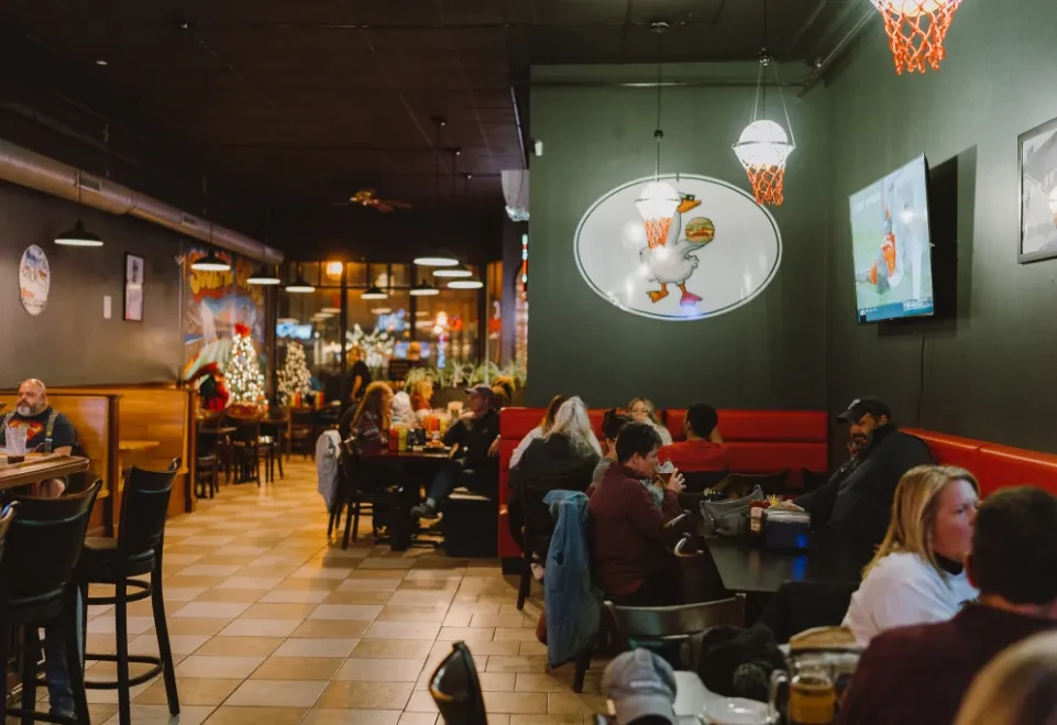 Casual sports bar interior with diners, warm lighting, and festive decor.
