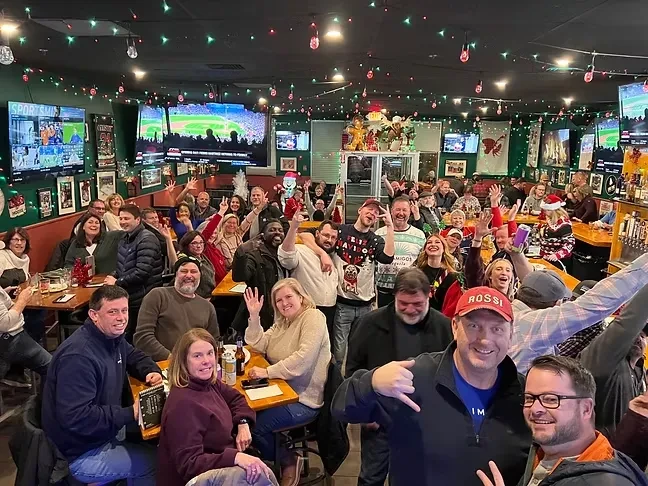 Large group of cheerful people celebrating Christmas in a festive bar.