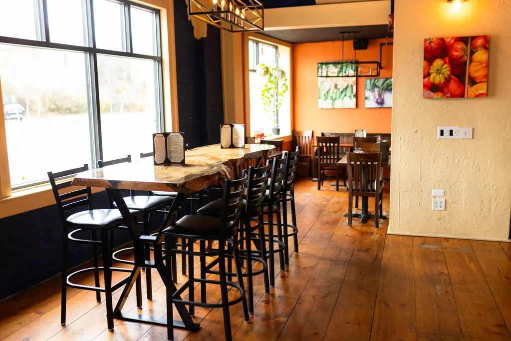 Rustic-modern restaurant interior with live-edge communal table and warm dining areas.