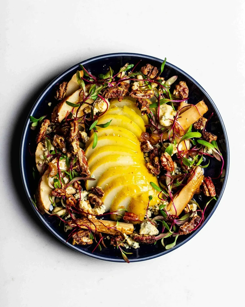 Salad in blue bowl, with sliced pear, blue cheese, pecans, microgreens.
