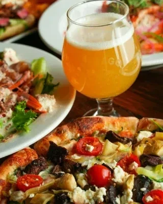 Overhead view of a pizza, salad, and a frothy beer.