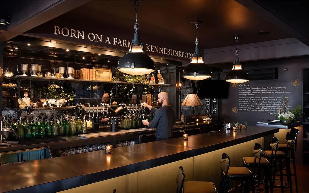 Bartender at a dimly lit bar with a 'BORN ON A FARM' sign.