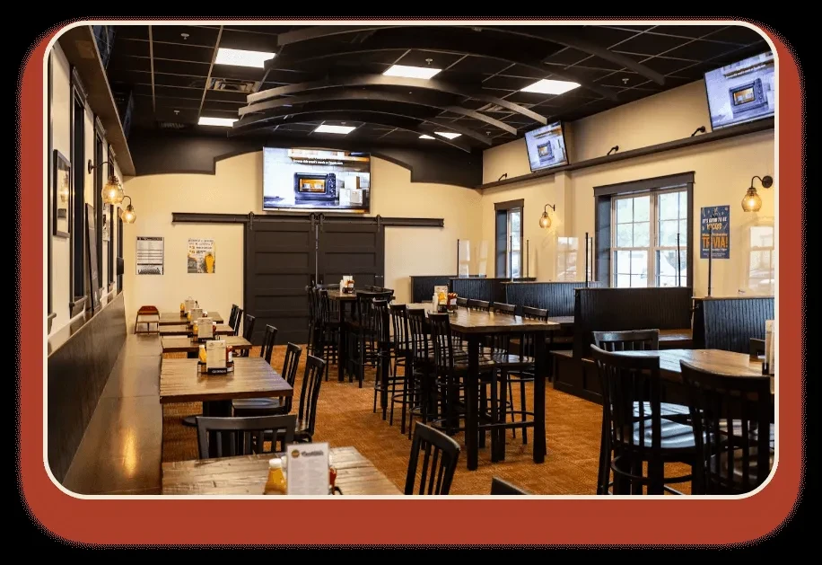 Interior of a modern, empty restaurant with various tables, booths, and TVs.