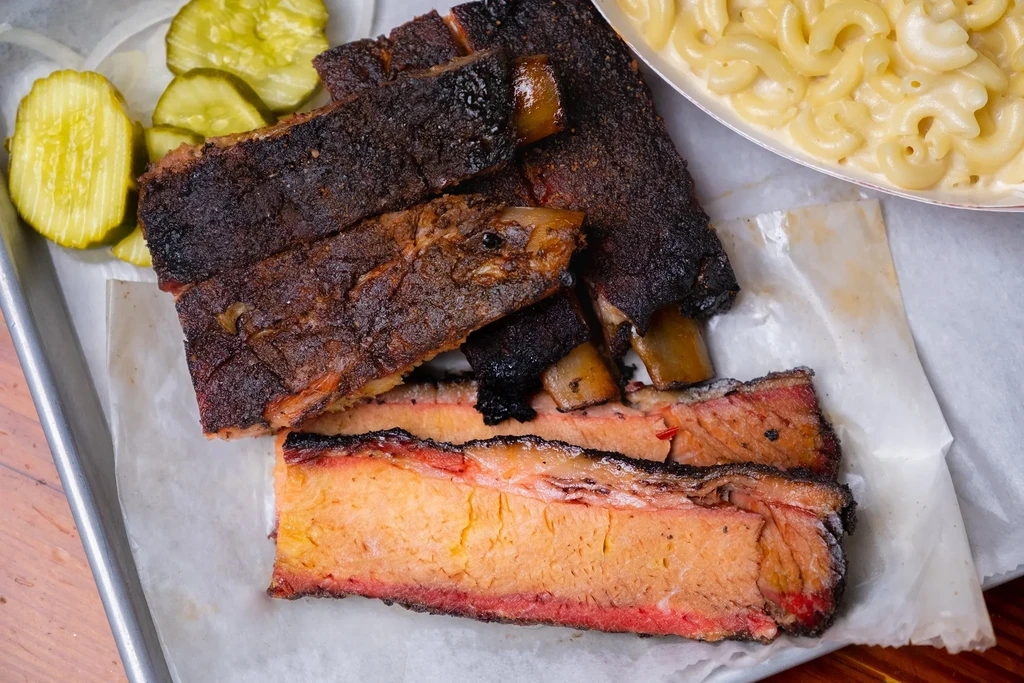 Close-up of barbecued ribs, brisket, pickles, and macaroni and cheese.