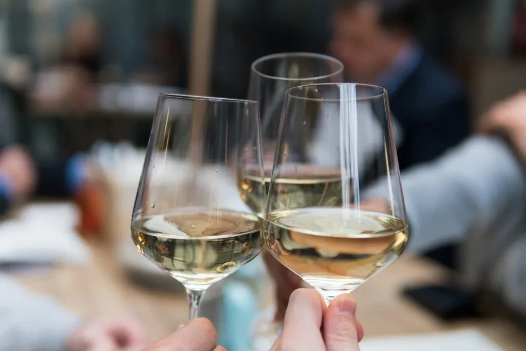 Three white wine glasses with condensation, held in a toast.