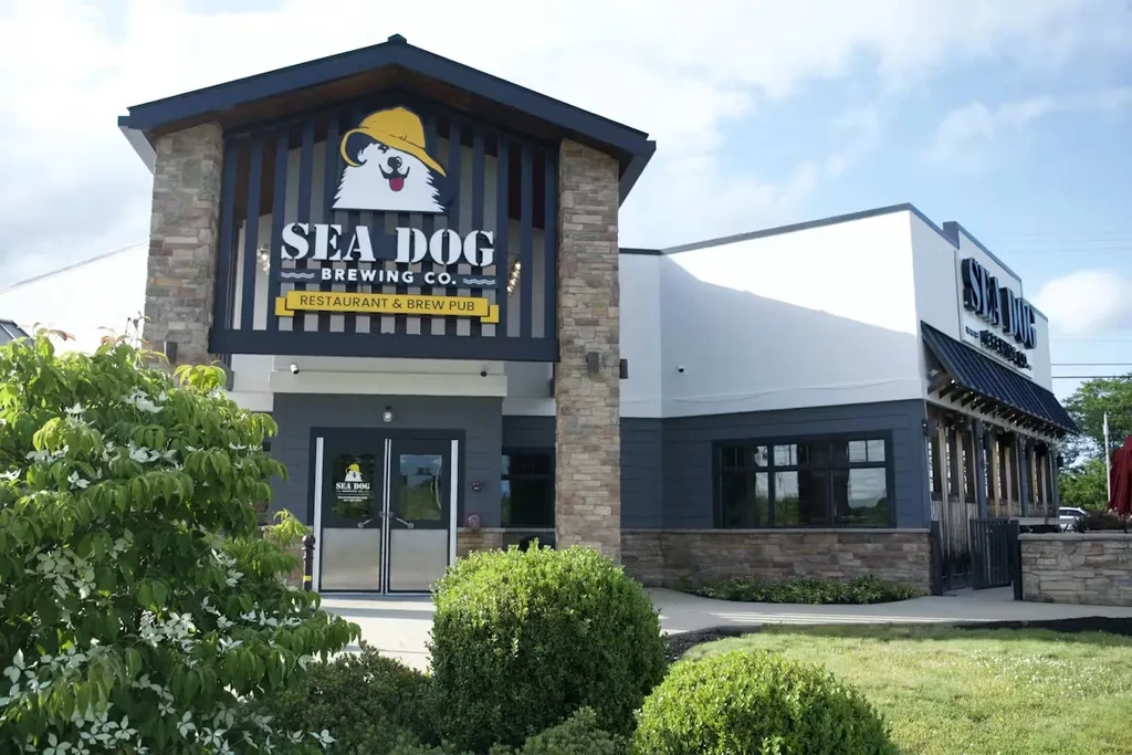 Sea Dog Brewing Co. exterior with dog logo, mixed siding, and landscaping.