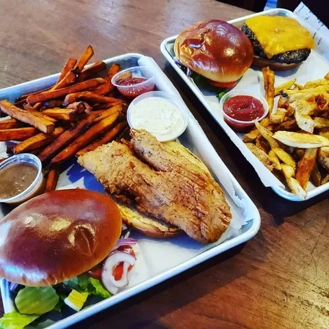 Two trays: fried fish sandwich with sweet potato fries, a cheeseburger.