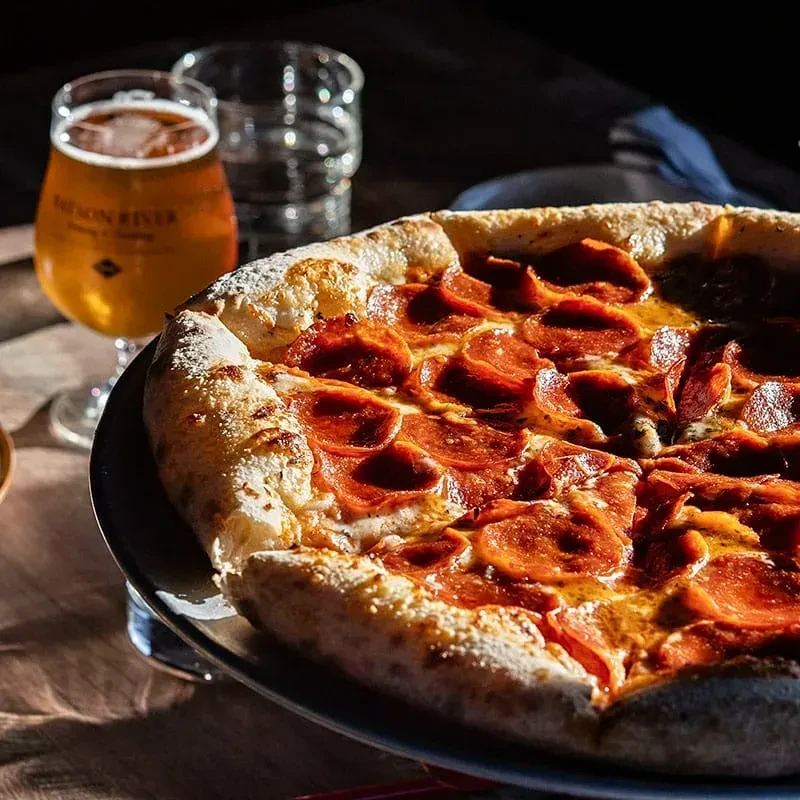 Close-up of pepperoni pizza with melted cheese, crispy pepperoni, and beer.