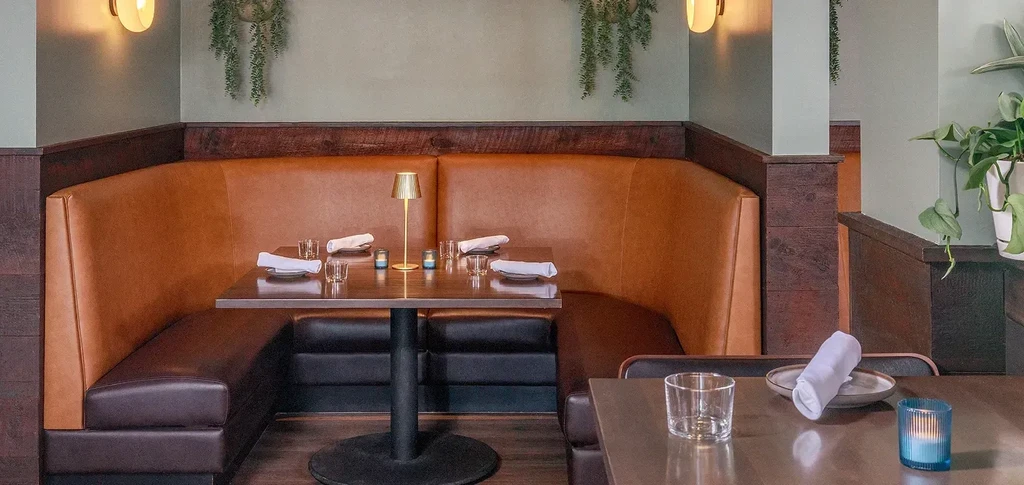 Warmly lit restaurant corner with cognac booth and set table.