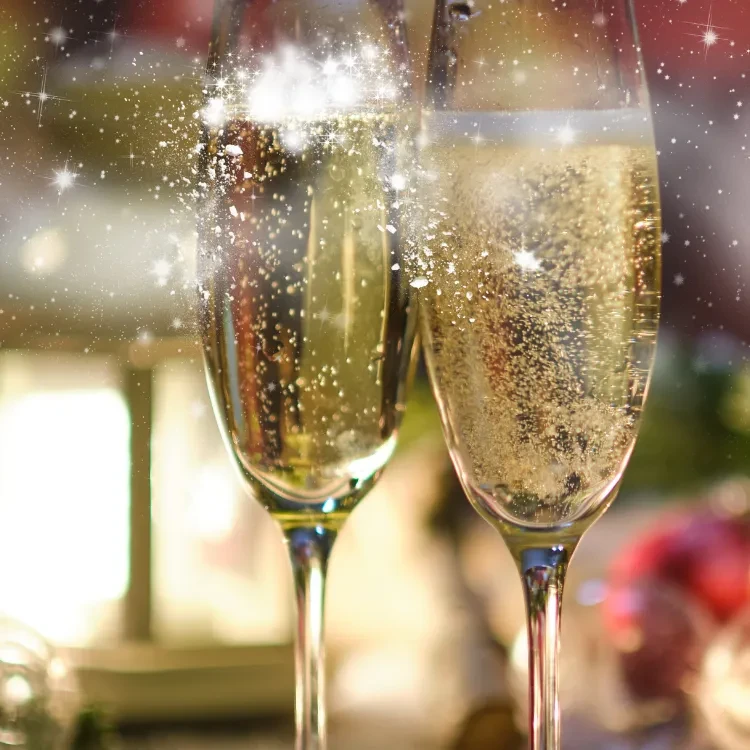 Two effervescent champagne flutes with golden sparkling wine and light effects.