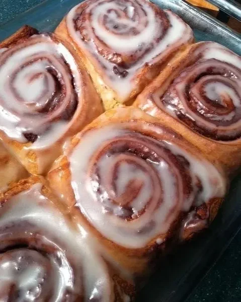 Close-up of several iced cinnamon rolls in a clear baking dish.