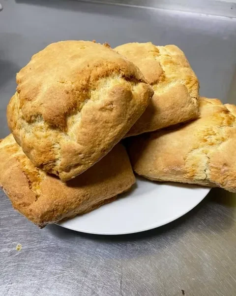 Four golden-brown rustic bread rolls on a white plate.
