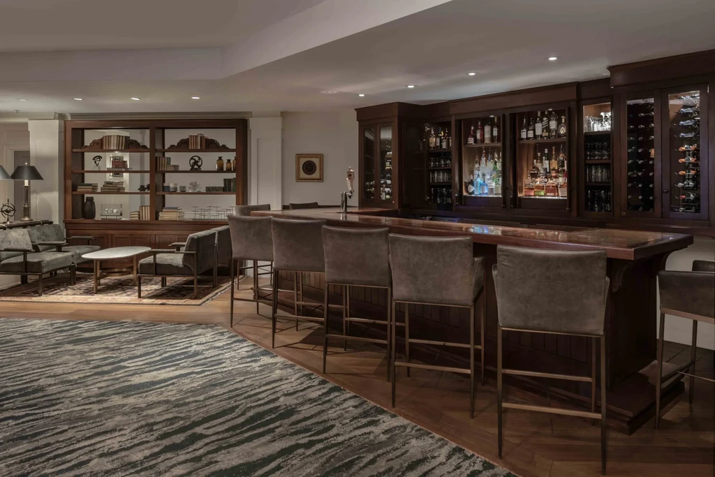 Sophisticated dark wood bar and lounge with comfortable seating and books.
