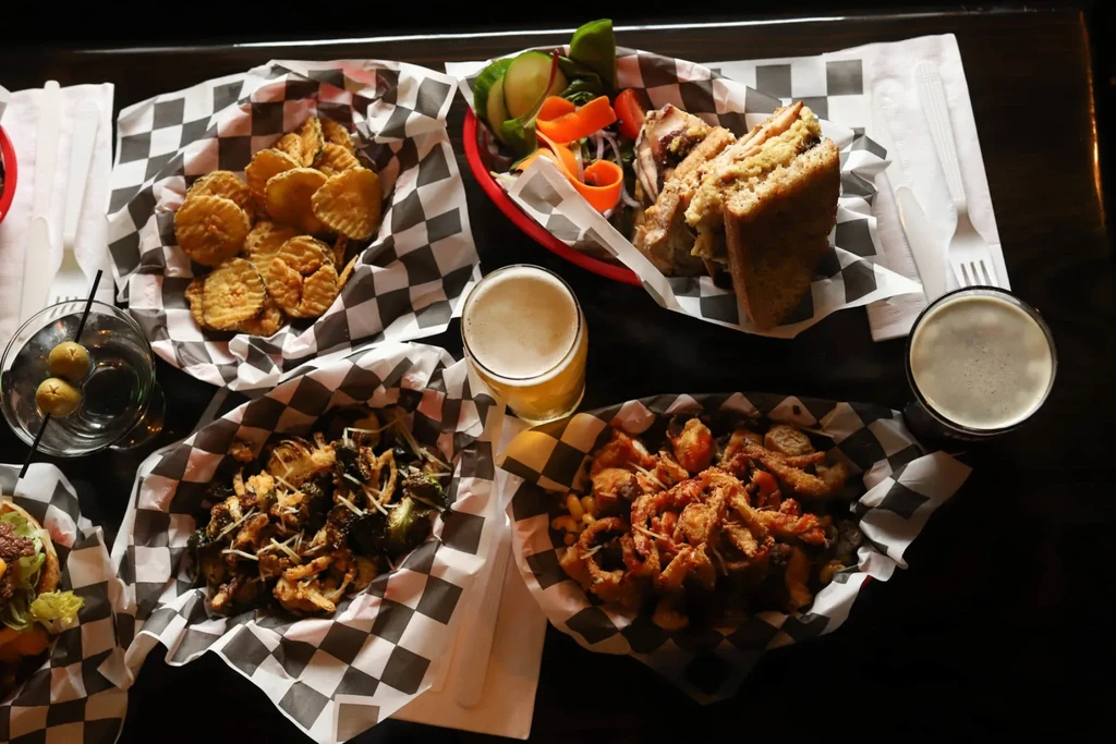 Overhead view of fried foods, sandwich, roasted vegetables, and drinks.