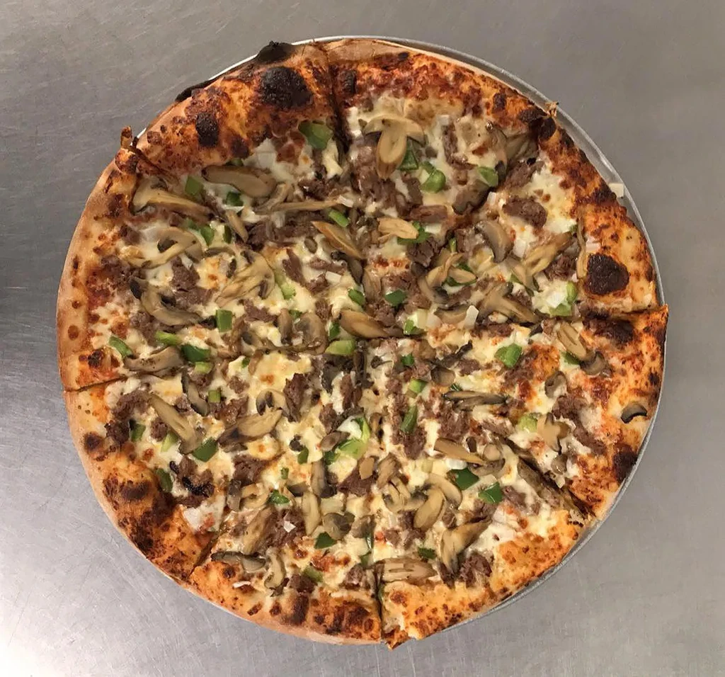 Pizza with melted cheese, ground meat, mushrooms, and green peppers, sliced.