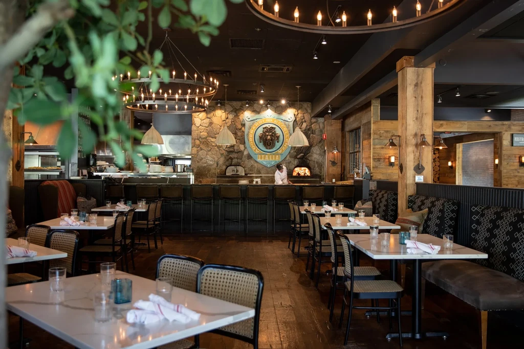 Restaurant interior: bar, two pizza ovens, lion emblem, and dining tables.