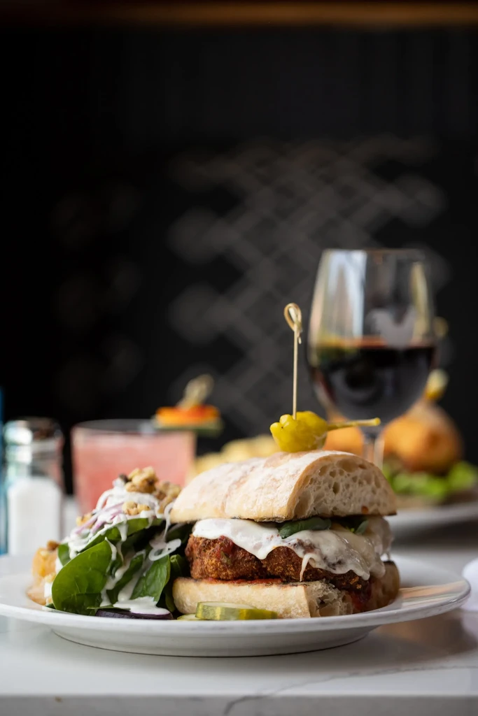 Well-composed burger, spinach salad, and red wine.