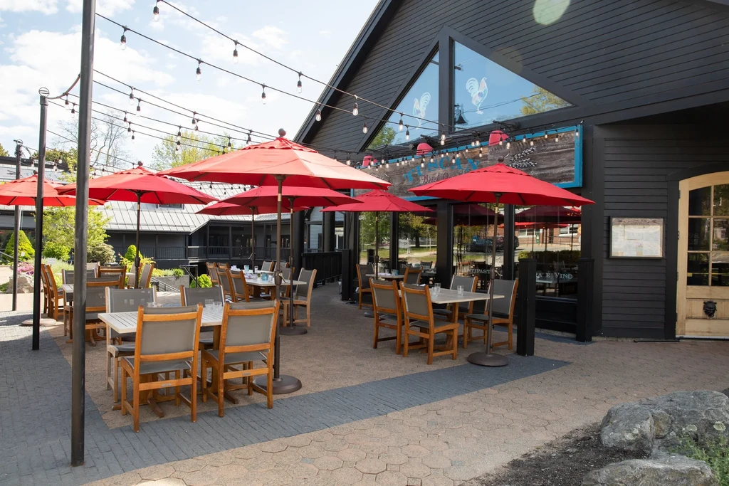 Outdoor restaurant patio with red umbrellas and a BRICK OVEN sign.