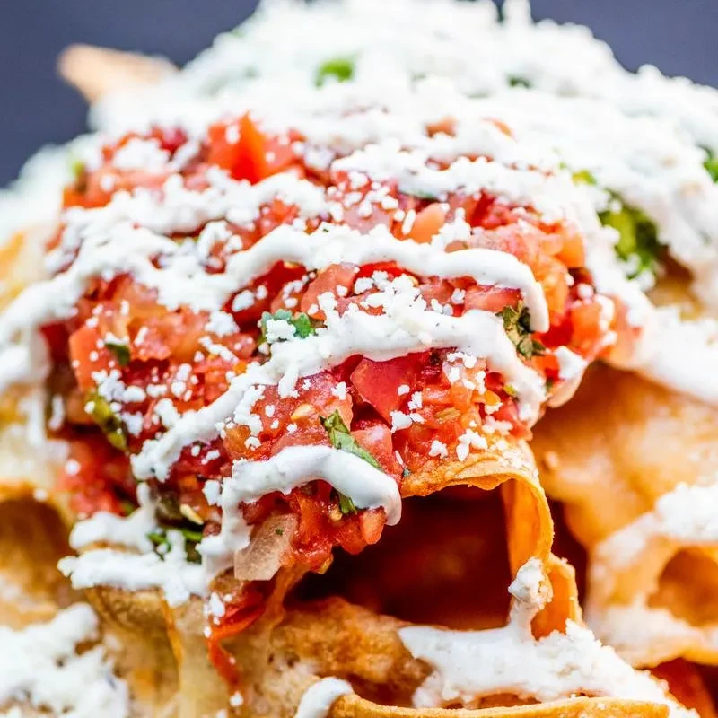 Colorful tortilla chips topped with pico de gallo, cheese, and cream sauce.