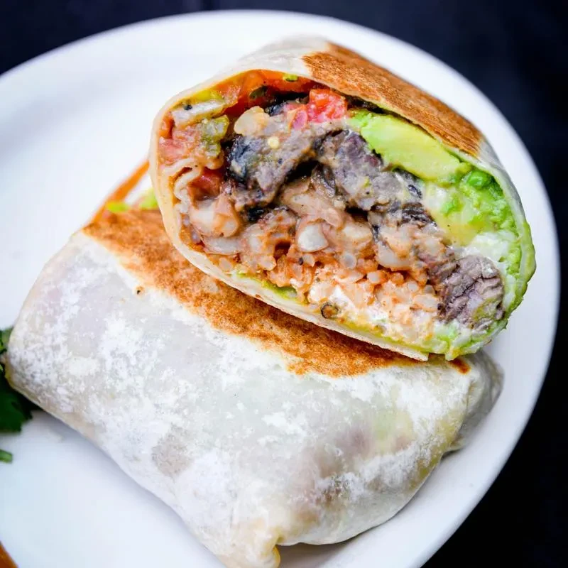 Close-up of a halved burrito revealing colorful layers of fillings.