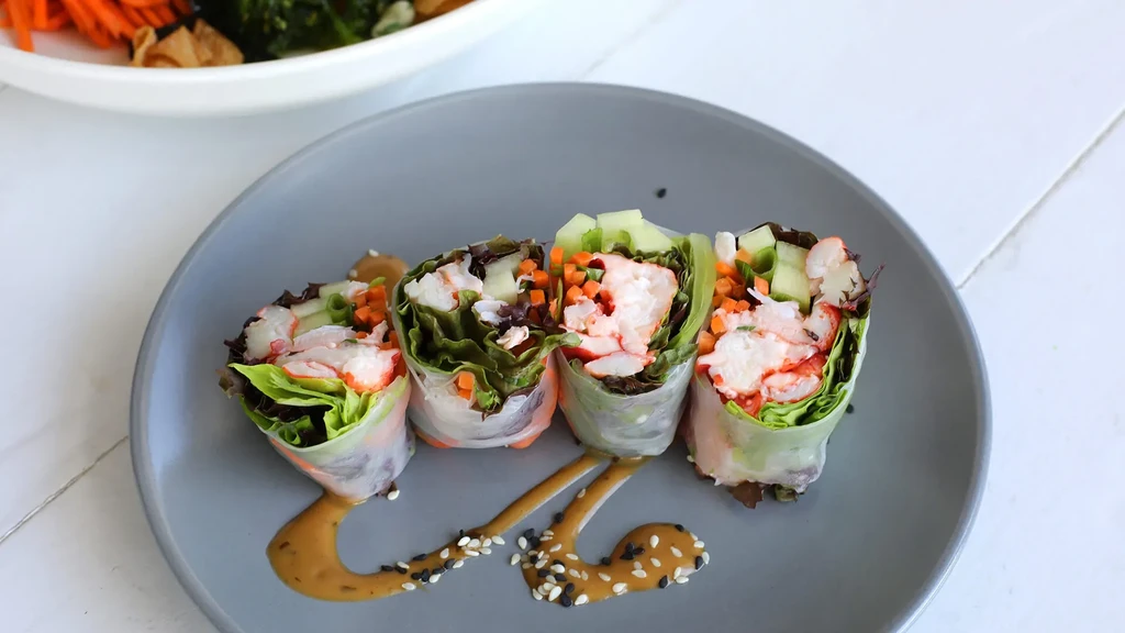 Four fresh Vietnamese spring rolls with colorful fillings and peanut sauce.