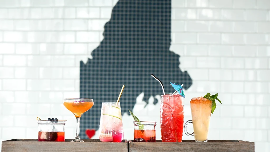 Six distinct cocktails on a counter, Maine silhouette background.