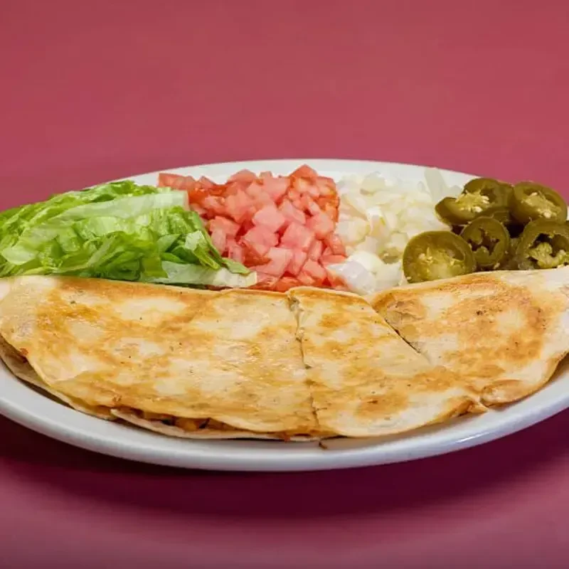Quesadilla, lettuce, tomatoes, onions, and pickled jalapeños on white plate.