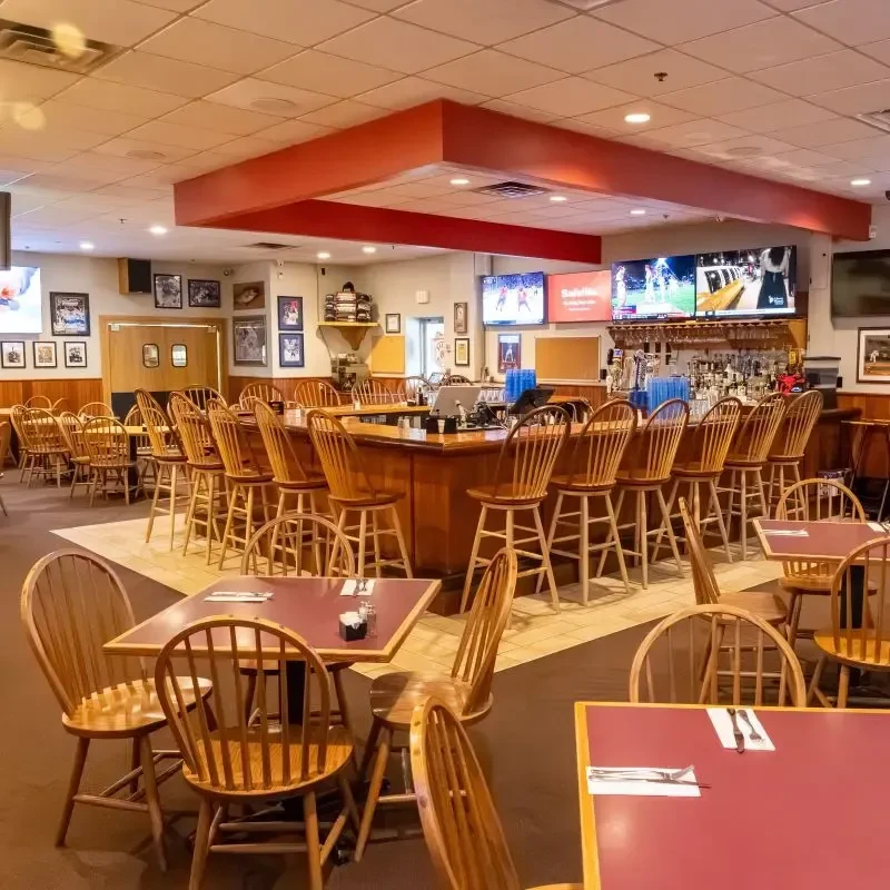 Casual restaurant interior with central bar, dining tables, and TVs showing sports.