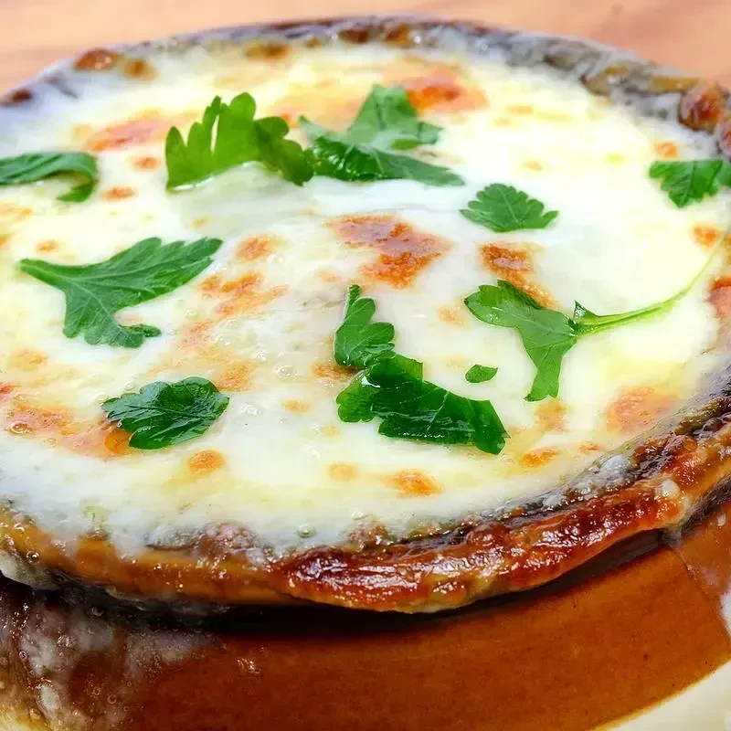Steaming French onion soup topped with bubbly browned cheese and parsley.
