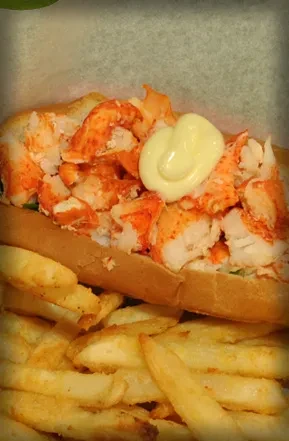 Toasted lobster roll with creamy sauce and golden french fries.