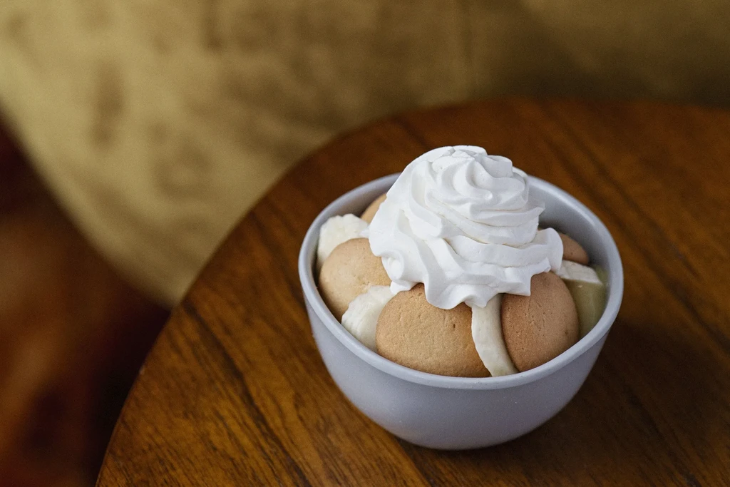 Banana pudding, topped with whipped cream, vanilla wafers, and banana slices.