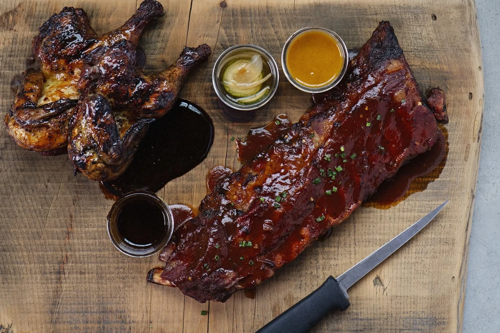 Rustic board with glazed chicken, BBQ ribs, and dipping sauces.