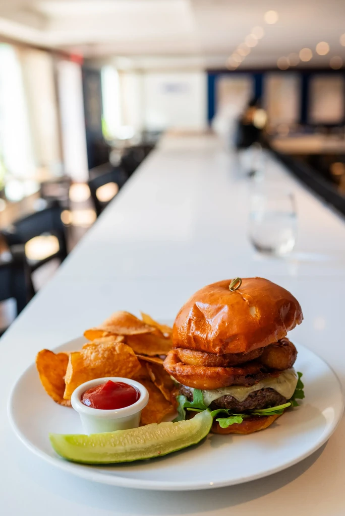 Gourmet burger, chips, ketchup, and pickle in a modern restaurant.