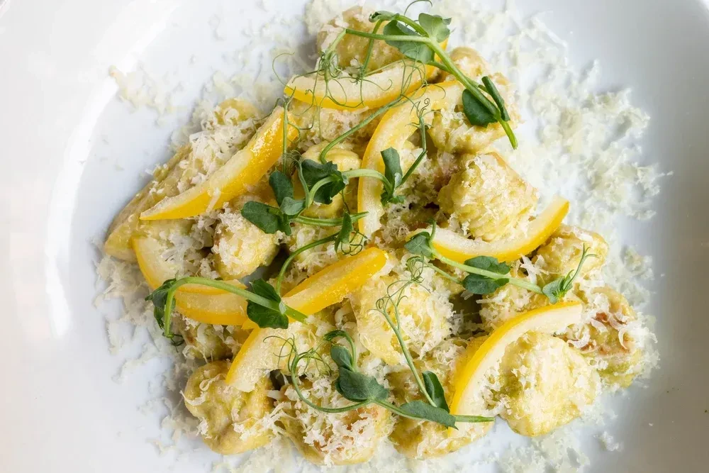 Light green gnocchi with white cheese, lemon, and microgreens.