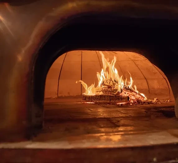 Interior view of a traditional brick oven with a roaring wood fire.