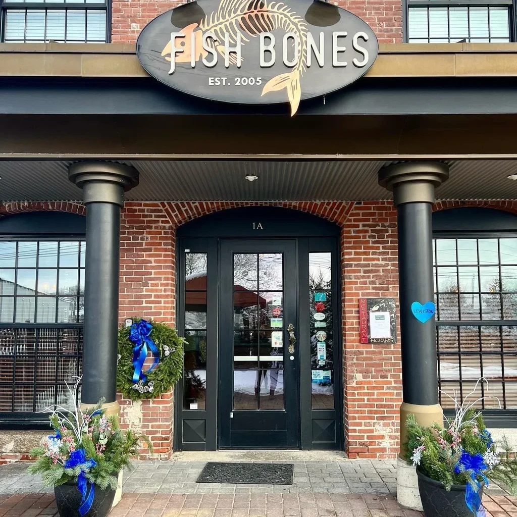 "FISH BONES" restaurant entrance, brick building with sign and seasonal decorations.