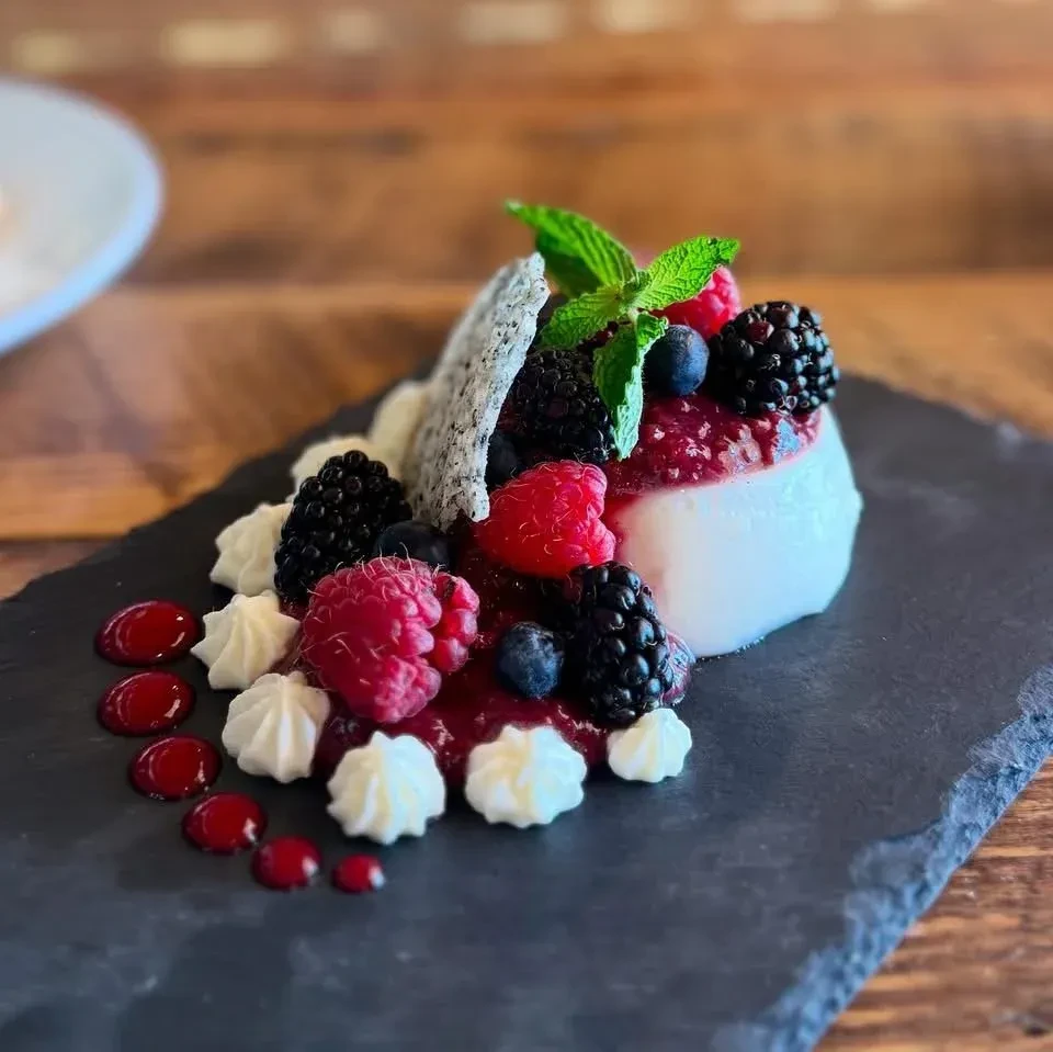 White berry dessert with mint, cream, wafer, on slate.