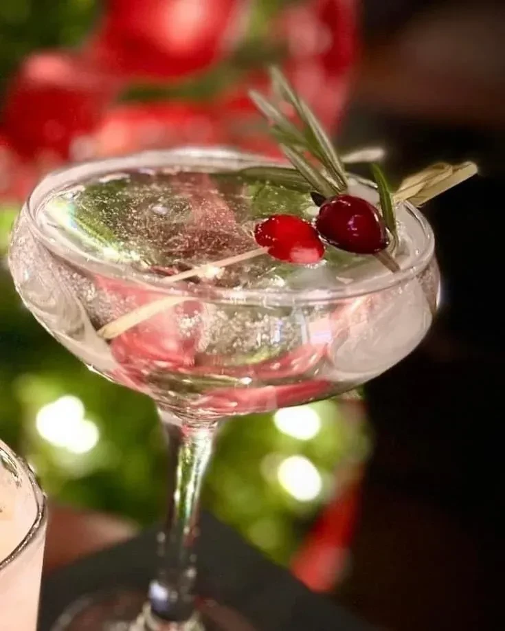 Festive sparkling cranberry rosemary cocktail in an elegant etched coupe.