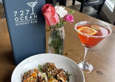 Red cocktail, crispy food, and '727 OCEAN SUNSET BAR' menu.